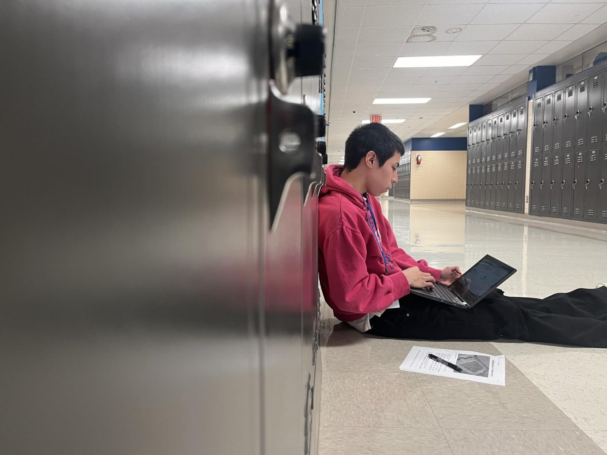 Student completes work on chromebook in a quiet hallway. 